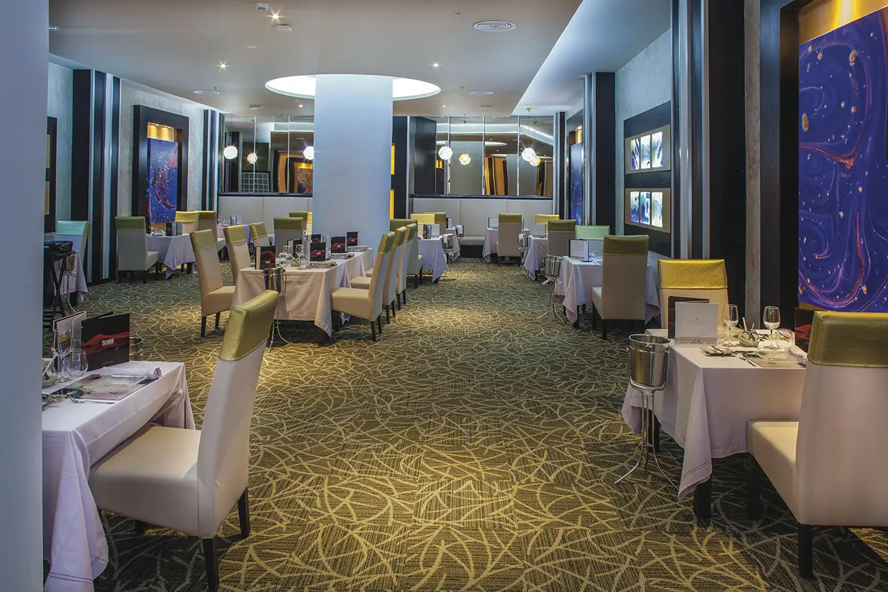 Elegant gourmet restaurant at Hotel Riu Palace Antillas, featuring stylish decor and well-set tables.