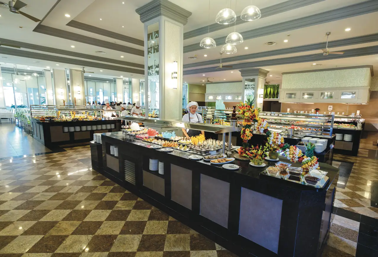 Elegant buffet setup at Hotel Riu Palace Antillas' main restaurant with chefs and decorative displays